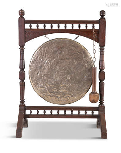 AN OAK AND BEATEN BRASS DINNER GONG, 19th century, the circular panel suspended from a turned oak