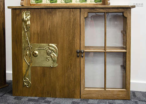 A contemporary oak cabinet, opening to reveal shelved interior decorated with Art Nouveau brass door