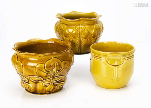 Three British pottery ochre coloured moulded jardinieres, including a stylised flower head on a