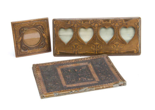 An Art Nouveau leatherette four division heart shape photograph frame, with tooled decoration of