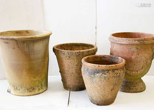 A quantity of terracotta plant pots, comprising a large circular squat lobed example with lobed