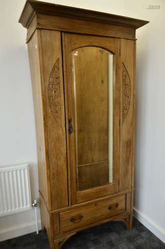 An Art Nouveau satin walnut single wardrobe, with mirrored bevelled arched door above a base