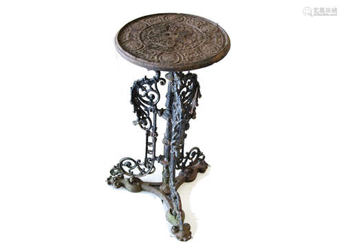 A cast iron garden table, the small circular top with moulded design on single pedestal with three