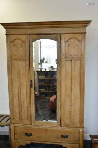 An Art Nouveau oak veneered and inlaid wardrobe, with middle bevelled glass arched door flanked by