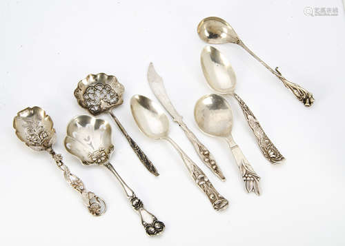 A collection of continental white metal Art Nouveau caddy spoons, butter knives, preserve spoons,