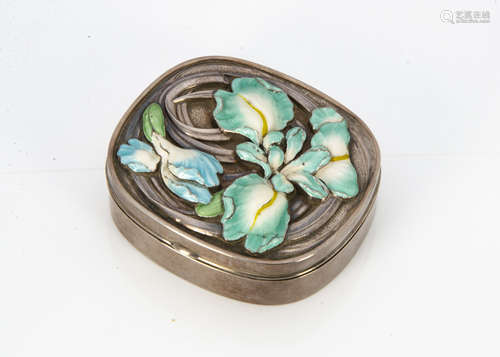 A white metal and enamel oval box, the hinged lid with embossed floral design of a lily in green and