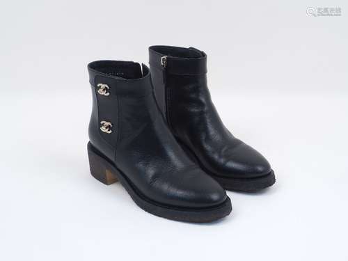 A pair of Chanel leather ankle boots, designed in black, with distinctive Chanel logo white metal