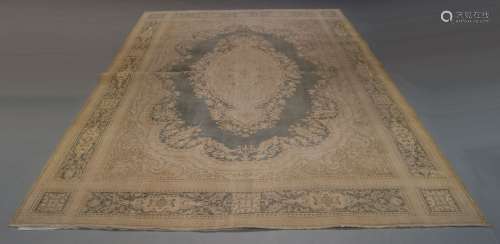 A Persian style carpet, of recent manufacture, with central ivory medallion medallion on faded green