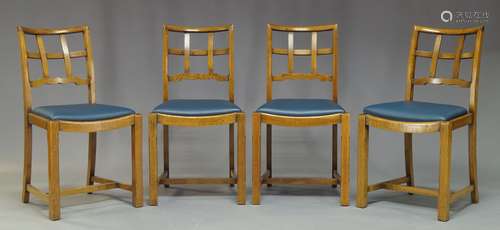 A set of four Cotswold school oak dining chairs, with lattice backs, above blue leather drop in