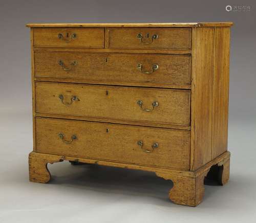 A George III oak chest, with two short over three long graduated drawers, raised on shaped bracket