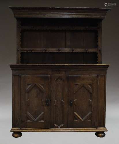 An oak dresser, 18th Century and later, the plate rack with two shelves, each with a series of pegs,