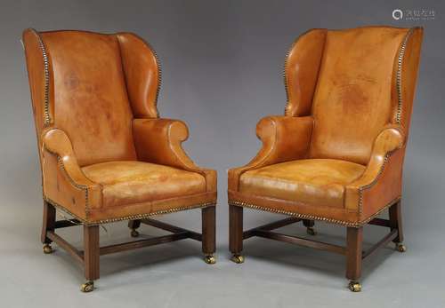 A pair of George III style wingback armchairs, mid 20th Century, with tan leather upholstery and