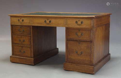 An Edwardian oak partner's desk, the rectangular top inset with later writing surface, above an