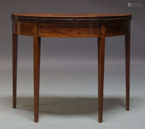 A George III mahogany demi-lune tea table, with fold over top, above frieze inlaid with paterae,