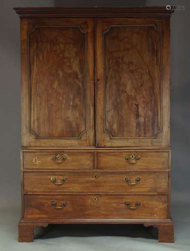 A George III mahogany linen press, the dentil moulded cornice above two panelled doors enclosing