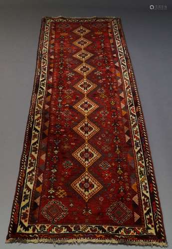 A Kazak runner, late 20th Century, with nine lozenge medallions in deep red field, with ivory main