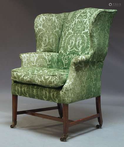 A George III style wing back armchair, 20th Century, with green floral pattern upholstery and one