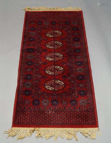 A Tekke rug, with five guls in a deep red field, 137cm x 68cm, together with a Caucasian rug, with