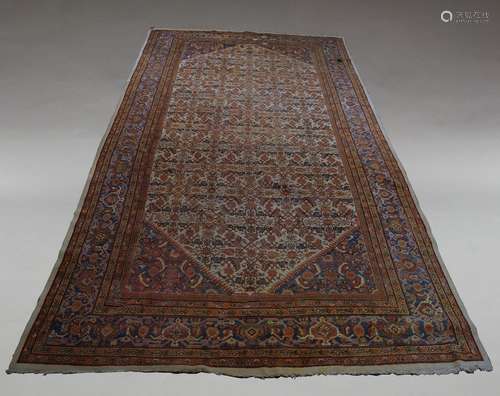 A large West Persian carpet, with repeat flowerhead design in ivory field and indigo main border,