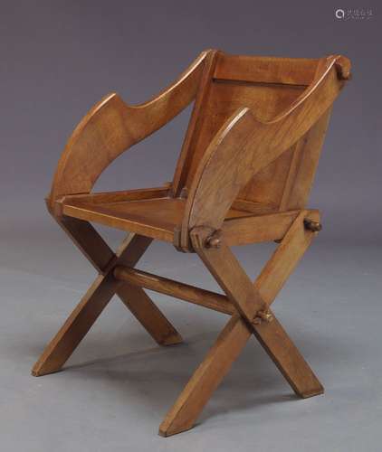 An oak Glastonbury armchair, early 20th Century, the square panelled back with shaped arms, on x-