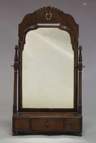 A Queen Anne walnut toilet mirror, the moulded frame with pierced fretwork top, on turned