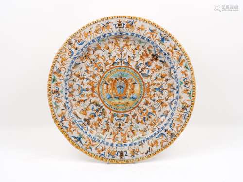 A large early 20th century Majolica charger, the centre decorated with a crest held by two putti,