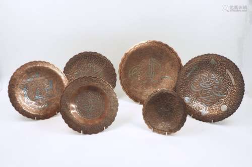 A collection of graduated Cairo ware plates, each with scalloped rims and white metal inlaid motifs,