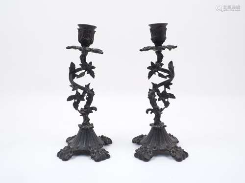 A pair of bronze coloured candlesticks, early 20th century, each designed with vine form stems,