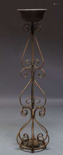 A wrought iron torchere stand, late 19th, early 20th Century, with copper bowl on open wrought