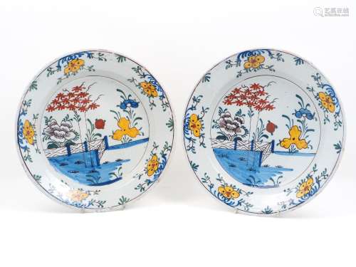 A pair of Delft ware chargers, 18th century, each designed with stylised polychrome naturalistic