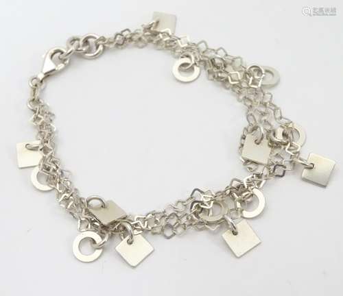 A silver and white metal triple-chain bracelet, each strand mounted with alternating squares and