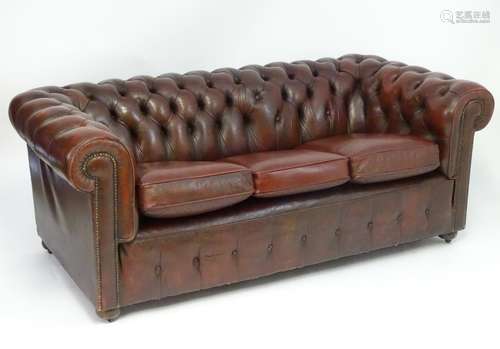 A 20thC oxblood leather Chesterfield three seat sofa, with button back upholstery, scrolled arms and