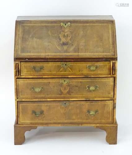 A 20thC walnut bureau with a fall front above three long graduated drawers with brass handles and