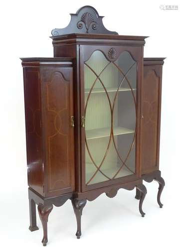 An Edwardian mahogany china cabinet with a carved upstand above an astragal glazed door flanked by