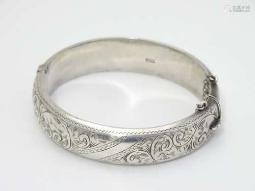 A silver bangle formed bracelet with engraved acanthus scroll decoration. Hallmarked Birmingham 1959