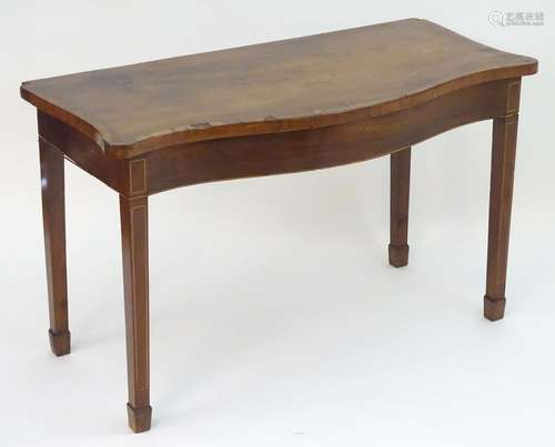 A late 18thC / early 19thC mahogany serving table with a serpentine and cross banded top above