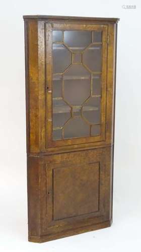 An early 19thC burr elm double corner cupboard with a moulded cornice above an astragal glazed