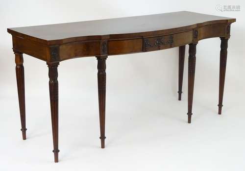 An early 20thC mahogany sideboard with a shaped top, a carved apron depicting swags and bows flanked