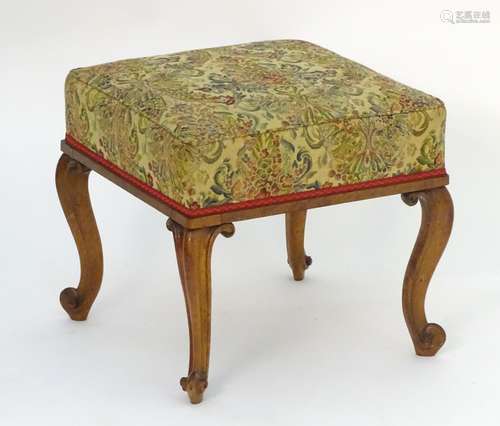 A 19thC walnut stool with squared upholstered top and raised on cabriole legs with french scrolled