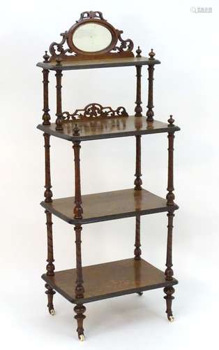 A Victorian walnut four tier whatnot with a mirrored gallery and fretwork decoration, having