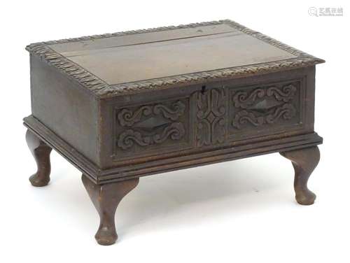 An 18thC oak bible box with a carved lid and carved face above a moulded base and later cabriole