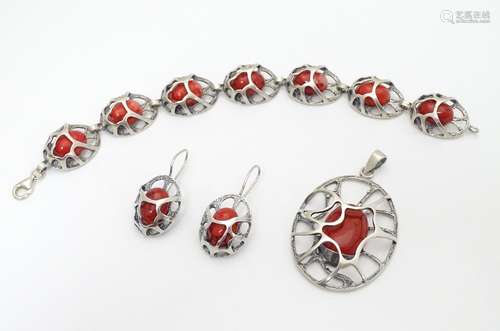 A suite of silver jewellery set with openwork detail and red hardstone cabochon. Comprising