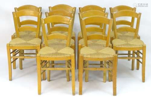 A set of ten chairs of beech construction with envelope rush seats and raised on shaped legs