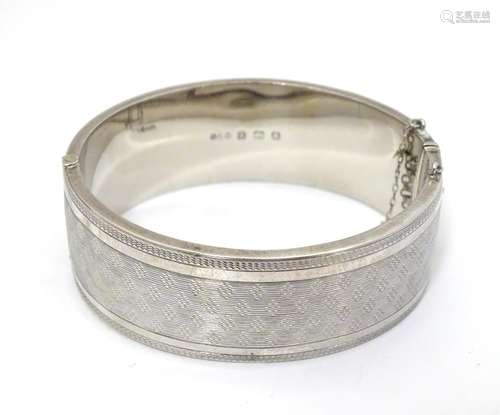 An Art Deco silver bracelet of bangle form with engine turned decoration. Hallmarked Birmingham 1932