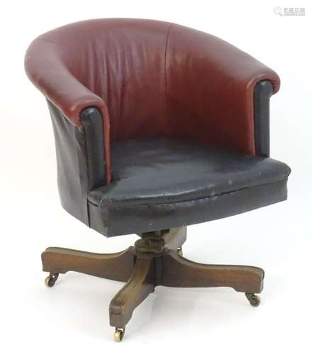 An early 20thC leather swivel armchair with an adjustable backrest and having four mahogany spokes