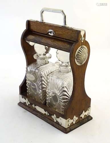 A late 19th / early 20thC two bottle oak tantalus with locking mechanism and decorative silver plate