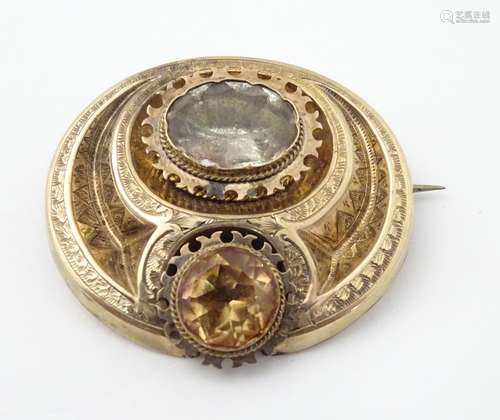 A 19thC yellow metal brooch with engraved decoration and set with two citrine coloured stones, the