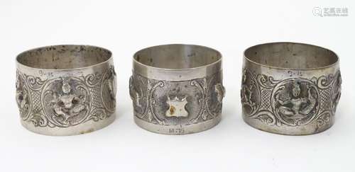 A pair of white metal napkin rings decorated with deity detail together with another with animal