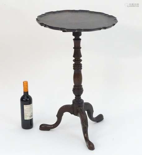 A Georgian mahogany tripod wine table with a pie crust top above a turned stem with carved