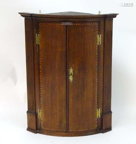 A Georgian oak corner cupboard with a moulded cornice above a carved frieze, having two doors with